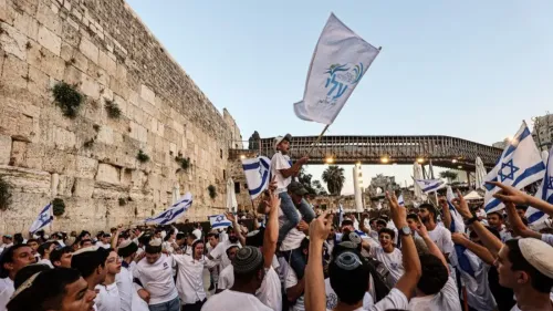 محتفلون يحملون أعلام إسرائيل في ساحة حائط المبكى، مع أجواء من الفرح والتجمع، في سياق الأحداث السياسية الجارية.
