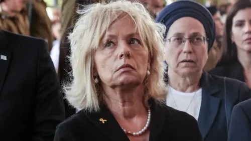 امرأة في مقدمة الصورة تبدو جادة، تحمل تعبيرًا قلقًا، بينما تظهر شخصيات أخرى في الخلفية. تعكس الصورة أجواء اجتماع سياسي حول السيطرة المدنية في الضفة الغربية.