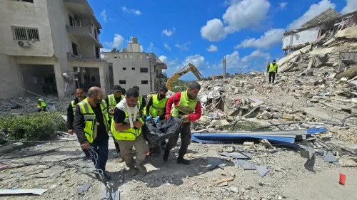 فرق إنقاذ تحمل جثة من تحت الأنقاض في منطقة تعرضت للقصف الإسرائيلي، مع مشهد من الدمار والمباني المهدمة في الخلفية.