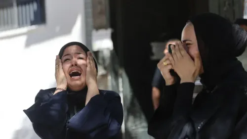 امرأتان ترتديان الحجاب تعبران عن حزن شديد بالبكاء في مشهد يعكس مأساة المدنيين الفلسطينيين في غزة جراء إطلاق النار الإسرائيلي.