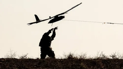 جندي إسرائيلي يطلق طائرة مسيرة في منطقة مفتوحة، مما يعكس التقدم التكنولوجي في المجال العسكري وسط التوترات المستمرة.