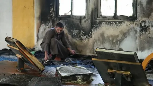 شخص فلسطيني يجمع الكتب المحترقة في مسجد تعرض للحرق من قبل مستوطنين في سلفيت، مما يعكس تصاعد العنف ضد الفلسطينيين.