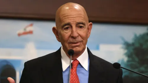 تظهر الصورة توم باراك، المستثمر العقاري والمبعوث الأمريكي، أثناء حديثه في مؤتمر، مع خلفية تحمل علم لبنان.