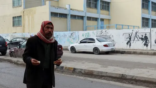 رجل مسن يقف في الشارع بالقرب من مدرسة، ممسكًا بقطعة خبز، بينما تظهر سيارات وم graffiti على الجدران، مما يعكس التحديات الاقتصادية.