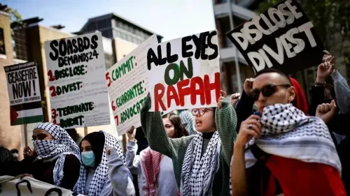 طلاب يحملون لافتات خلال احتجاج يطالب بالاستثمار الأخلاقي ودعم حقوق الفلسطينيين، مع التركيز على ضرورة إنهاء الاستثمارات في الشركات المتورطة.