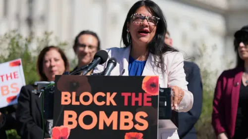 النائبة Rashida Tlaib تتحدث خلال مؤتمر صحفي، حاملة لافتة تطالب بوقف القنابل، وسط مجموعة من المؤيدين أمام مبنى الكونغرس.