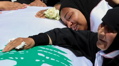 امرأتان ترتديان الحجاب، تتلمسان علم لبنان، بينما تعبر إحداهما عن مشاعر الحزن والأمل، في سياق ذكرى التحرير من الاحتلال.