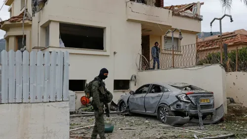 مقاتل من حزب الله يقف أمام منزل مدمر وسيارة متضررة، في سياق التصعيد العسكري على الحدود اللبنانية الإسرائيلية.