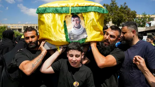 مراسم تشييع في لبنان، حيث يحمل رجلان نعشًا مغطىً بالصفراء مع صورة، بينما يظهر طفل في المقدمة يعبر عن الحزن.