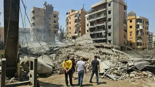 تظهر الصورة آثار الغارات الجوية الإسرائيلية في الضاحية الجنوبية لبيروت، حيث تتواجد مبانٍ مدمرة وركام، مع مجموعة من الأشخاص يتفقدون الأضرار.