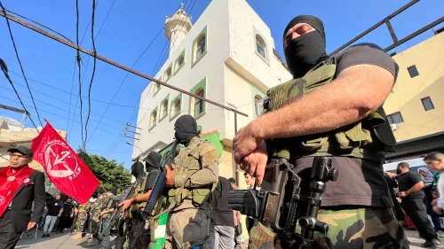 مسلحون فلسطينيون يرتدون أقنعة ويستعرضون أسلحتهم في مخيم للاجئين في لبنان، مع وجود علم أحمر لجبهة التحرير الفلسطينية.