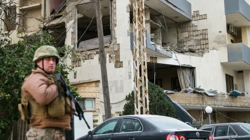 جندي لبناني يقف أمام مبنى متضرر من القصف، مما يعكس التوترات المستمرة بين الجيش وحزب الله في ظل الصراع الإسرائيلي اللبناني.