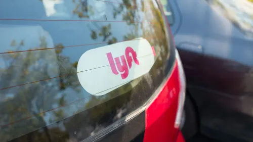 شعار شركة Lyft على نافذة سيارة حمراء، يعكس تسوية قانونية ضخمة في كاليفورنيا حول تصنيف سائقي التطبيقات كمتعاقدين مستقلين.