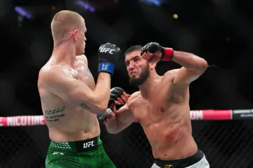 إسلام ماخاشيف يهاجم منافسه إيان ماتشادو جاري في قفص UFC خلال مباراة وزن 170 رطلاً ضمن UFC 330، مع آثار جروح وكدمات على وجهه.