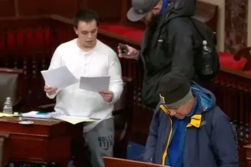 رجل يقف في قاعة مجلس الشيوخ الأمريكي يحمل أوراقًا، بينما يتواجد آخرون في الخلفية، خلال اقتحام مبنى الكابيتول في 6 يناير 2021.