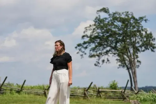 امرأة تسير في منطقة مفتوحة بجوار شجرة، تعكس مشاعر القوة والتحدي بعد تجربة الاعتداء الجنسي، في سياق قضية قانونية.