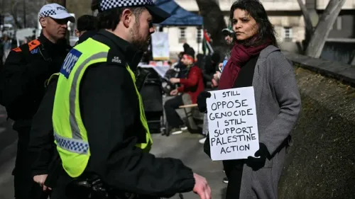 امرأة تحمل لافتة مكتوب عليها "ما زلت أعارض الإبادة الجماعية، ما زلت أدعم العمل الفلسطيني" أثناء احتجاج في لندن، مع وجود شرطة بالقرب منها.