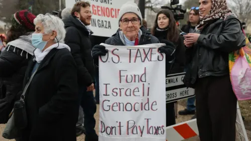 امرأة مسنّة تحمل لافتة مكتوب عليها "ضرائب الولايات المتحدة تمول الإبادة الجماعية الإسرائيلية" في مظاهرة تعبر عن التعاطف مع الفلسطينيين.