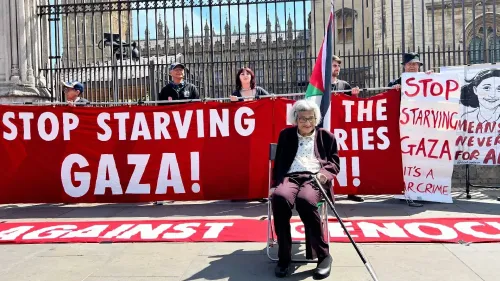 امرأة مسنّة تجلس على كرسي متحرك أمام لافتات تطالب بوقف تجويع غزة، في احتجاج خارج داونينغ ستريت.