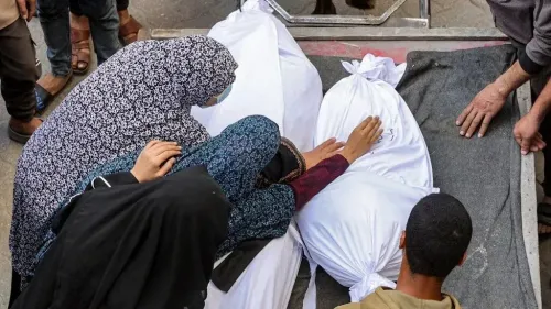 نساء وأطفال يشاركون في مراسم وداع، يلمسون أكياس الموتى المغلقة في غزة، وسط أجواء من الحزن الشديد نتيجة القصف الإسرائيلي.