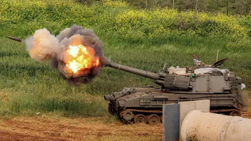 مدفع إسرائيلي يطلق قذيفة في منطقة زراعية بجنوب لبنان، مع تصاعد الدخان واللهب، في سياق التوترات العسكرية المتزايدة.