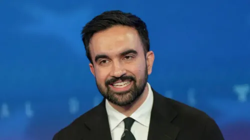 فوز زهران ممداني، عمدة مدينة نيويورك المنتخب، بابتسامة، مع خلفية زرقاء، يعكس نجاحه في جذب الناخبين من مختلف الأعراق.