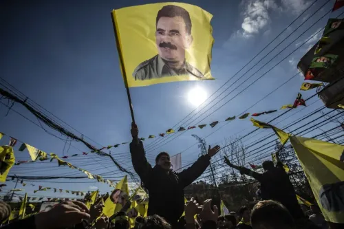 محتجون يحملون أعلاماً صفراء تحمل صورة عبد الله أوجلان، الزعيم المسجون لحزب العمال الكردستاني، خلال تجمع حاشد.