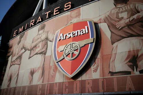 شعار نادي أرسنال لكرة القدم مع خلفية تُظهر لاعبين سابقين، يعكس التوتر حول حرية التعبير في ظل انتقادات لإدارة النادي.