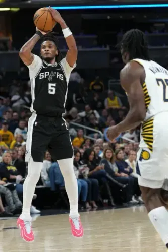 لاعب كرة سلة يرتدي زي فريق سان أنطونيو سبيرز، يقوم بتسديدة خلال مباراة ضد إنديانا بيسرز، مع جمهور خلفه.