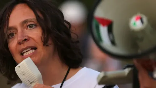 امرأة تتحدث عبر ميكروفون، تعبر عن دعمها لسجناء فلسطينيين مضربين عن الطعام في المملكة المتحدة، في سياق قضايا حقوق الإنسان.