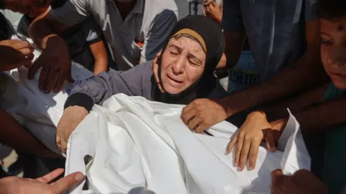 امرأة فلسطينية تبكي وهي تحيط بجثمان ملفوف، تعبير عن الألم والخسائر في غزة وسط استمرار الإبادة الجماعية والهجمات الإسرائيلية.