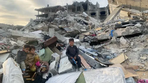 أطفال يجلسون على أنقاض منزل مدمّر في شمال غزة، يعبرون عن معاناتهم بعد الحرب الإسرائيلية وما خلفته من دمار.