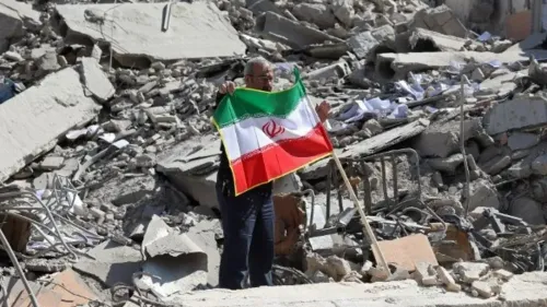 رجل يحمل علم إيران وسط أنقاض مبنى مدمر، مما يعكس آثار الصراع المستمر وتأثيره على المدنيين.