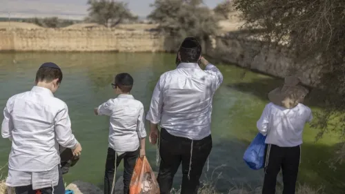 مجموعة من الأشخاص يرتدون ملابس بيضاء، يقفون بجوار مياه خضراء، مستعرضين منطقة تاريخية في الأراضي الفلسطينية المحتلة.