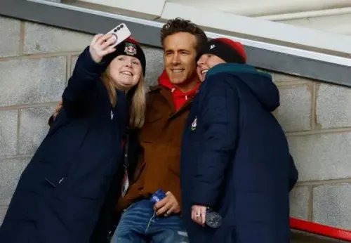 صورة لمشجعين من نادي ريكسهام يتناولون سيلفي مع أحد المالكين، مما يعكس حماسهم قبل مواجهة تشيلسي في كأس الاتحاد الإنجليزي.