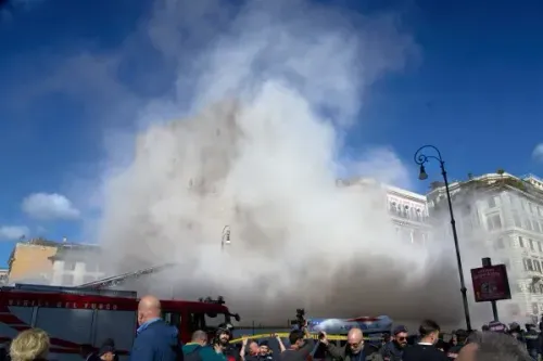 سحابة من الدخان تتصاعد من برج توري دي كونتي في روما بعد انهياره جزئيًا أثناء عملية ترميم، مع تجمع رجال الإطفاء والمشاهدين.