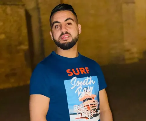 صورة لرجل شاب يرتدي قميصاً أزرق يحمل عبارة "Surf South Bay"، يظهر في خلفية غير واضحة. تعكس الصورة قضيته المتعلقة بالعنف البوليسي في تونس.