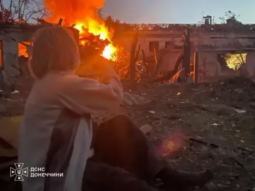 امرأة تجلس وسط دمار ناجم عن قصف روسي على مبانٍ في منطقة دونيتسك بأوكرانيا، تعبيراً عن تأثير الحرب على المدنيين والبنية التحتية.