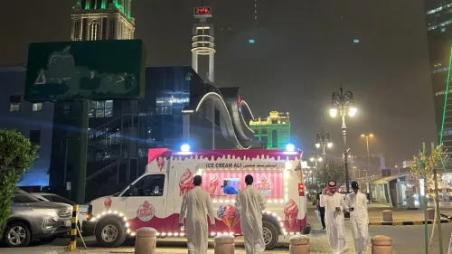 شاحنة آيس كريم تضيء في الليل، مع زبائن يرتدون الثوب السعودي، في مشهد يعكس الحياة الليلية في السعودية.