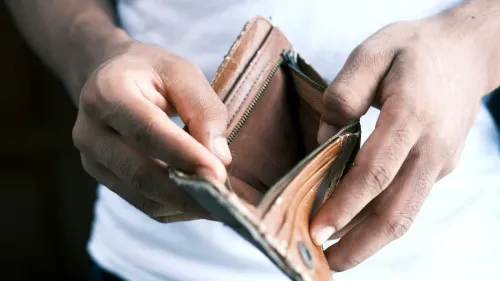 يدان تمسكان بمحفظة فارغة تعكس أزمة الفقر وتأثير ارتفاع تكاليف الغذاء والطاقة على دخل الفقراء بحلول 2050.