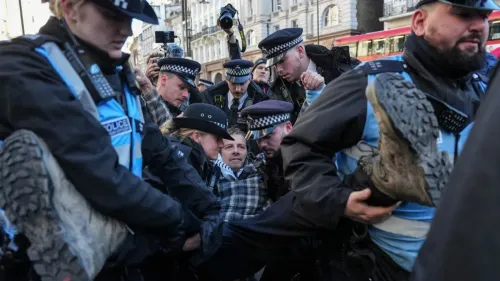 اعتقال متظاهر خلال احتجاج على حظر منظمة العمل الفلسطيني في اسكتلندا، مع وجود رجال شرطة ومصورين في الخلفية.