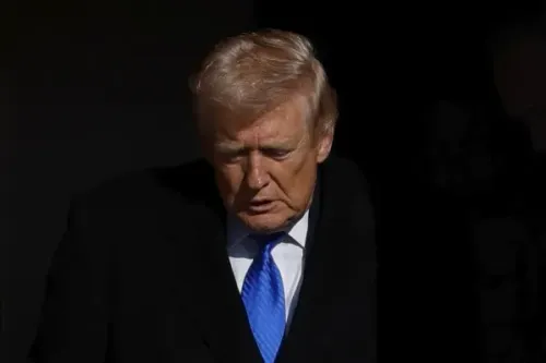 صورة لرجل يرتدي بدلة داكنة مع ربطة عنق زرقاء، يبدو عابسًا وهو يغادر مكانًا مظلمًا، مما يعكس أجواء التوتر السياسي المتعلقة بأمن المطارات.