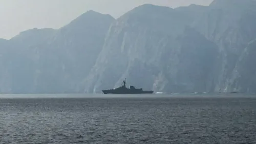 سفينة حربية تبحر في مياه مضيق هرمز، محاطة بالجبال، في ظل تصاعد التوترات بين إيران والولايات المتحدة.