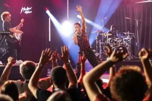 المغني D4vd يؤدي على المسرح أمام جمهور متفاعل، مع وجود فرقة موسيقية خلفه، وسط أضواء ملونة تعكس أجواء الحفلة.