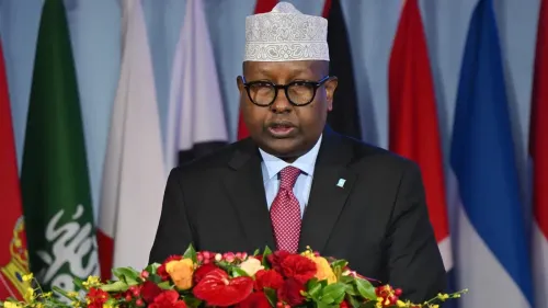 وزير الدفاع الصومالي أحمد معلم فقي يتحدث في مؤتمر، محاطًا بأعلام دولية، حول تورط بلاده في الصراع السوداني.