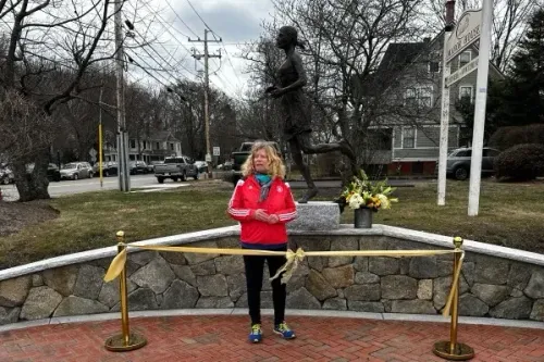 تمثال برونزي لامرأة تجري، يمثل Bobbi Gibb، أول امرأة تشارك في ماراثون بوسطن، يقف بجوارها في موقع الكشف عنه.