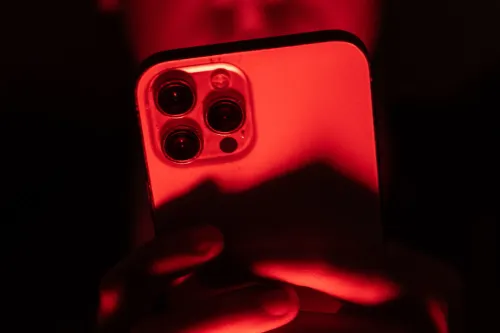 هاتف آيفون مضاء بضوء أحمر يعكس أهمية تحديث نظام iOS لحماية الأجهزة من ثغرات أمنية خطيرة في iOS 26.