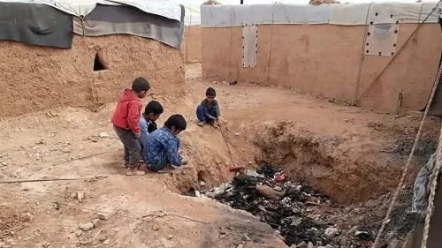 أطفال يلعبون بالقرب من مخيم الركبان للاجئين، مع خلفية من الخيام والظروف القاسية التي يعيشها السكان.