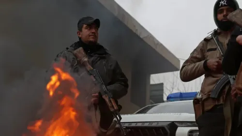 مقاتلون مسلحون يقفون بجوار نار مشتعلة، مع وجود سيارة شرطة خلفهم، في سياق التوترات الأمنية في شمال شرق سوريا.