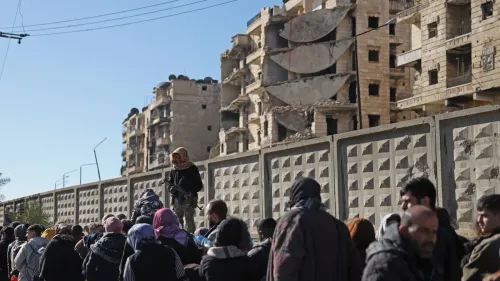 مشهد لمدنيين نازحين في حي الشيخ مقصود بحلب، مع وجود مبانٍ مدمرة في الخلفية، وسط تصاعد العنف بين القوات السورية والأكراد.